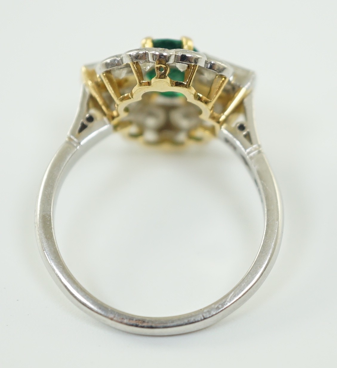 A modern platinum, oval cut emerald and baguette and round cut diamond set cluster ring